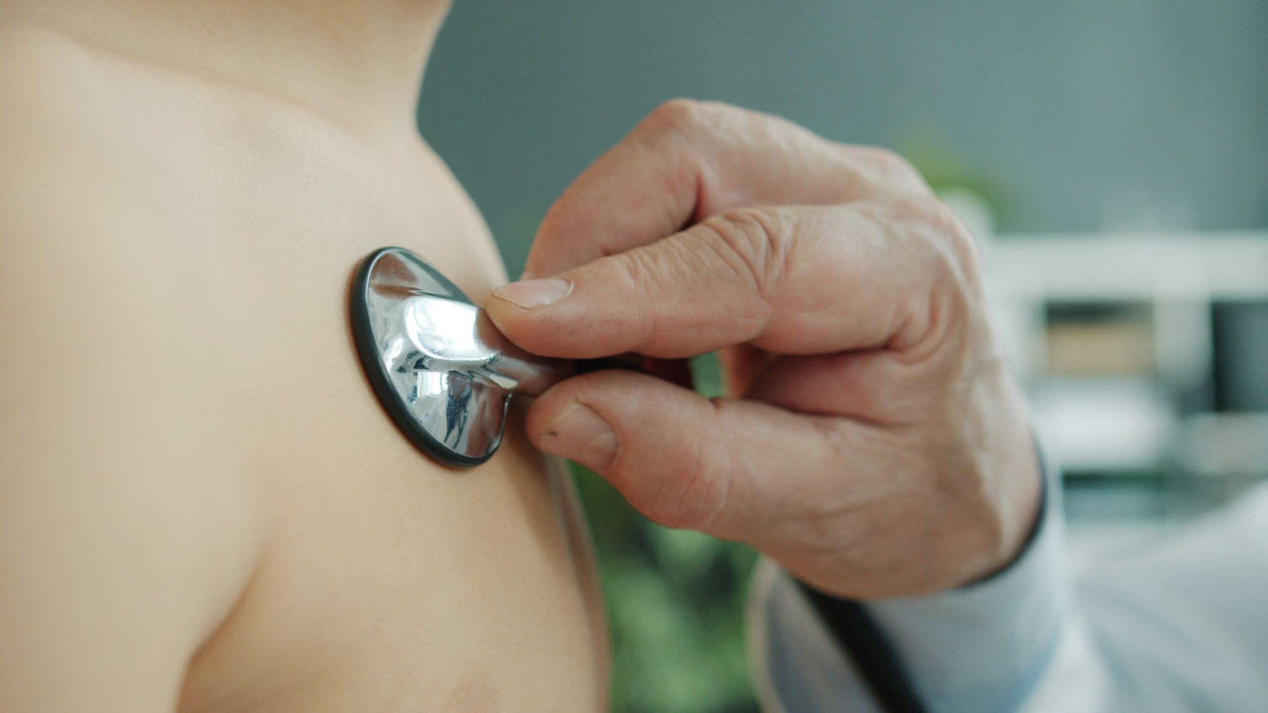 Close-up of a doctor using a stethoscope on a child's chest, indoors.